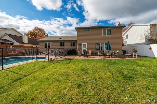 back of property with a fenced in pool, a yard, a fenced backyard, a chimney, and a patio area