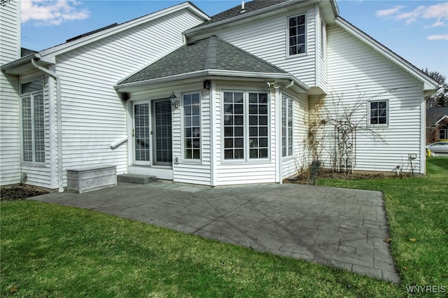 rear view of property with a patio area, a chimney, a yard, and roof with shingles