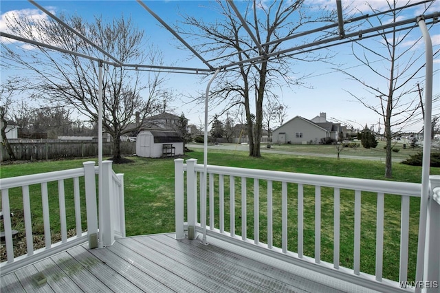 wooden deck with an outdoor structure, a yard, fence, and a storage unit