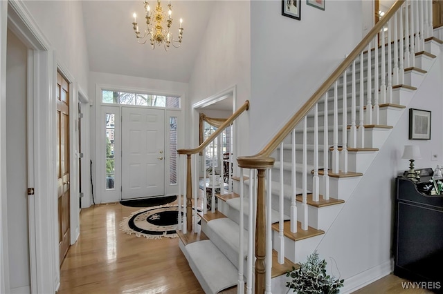 entrance foyer featuring a chandelier, wood finished floors, a wealth of natural light, and high vaulted ceiling