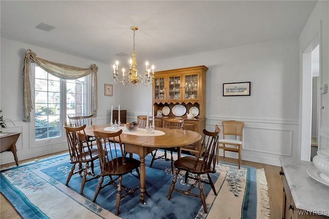 dining room featuring visible vents, wainscoting, a decorative wall, and an inviting chandelier