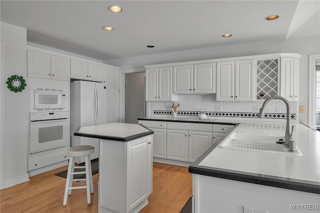 kitchen featuring a sink, white appliances, light wood-style floors, and white cabinetry