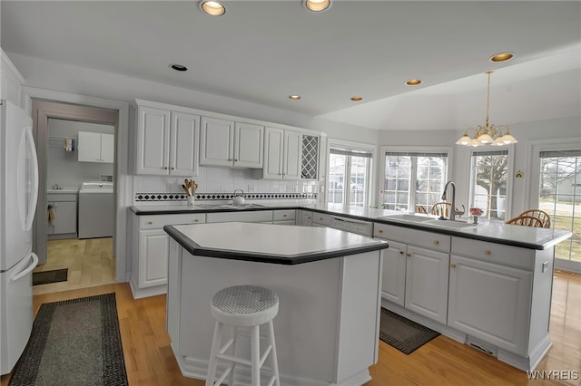 kitchen featuring a sink, a center island, freestanding refrigerator, decorative backsplash, and washer / dryer