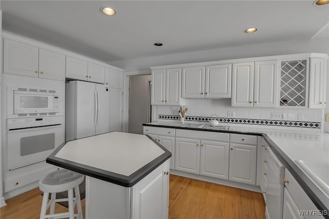 kitchen with white cabinetry, white appliances, light wood finished floors, and decorative backsplash