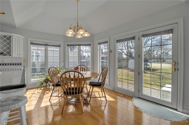 interior space with visible vents, lofted ceiling, plenty of natural light, and an inviting chandelier