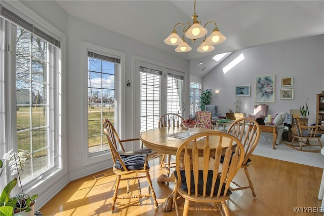 dining room featuring baseboards, visible vents, vaulted ceiling, light wood-type flooring, and a chandelier