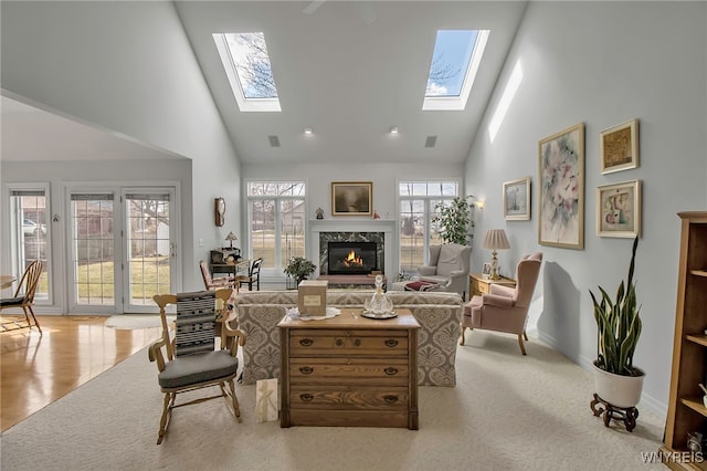 living room featuring wood finished floors, a skylight, a fireplace, and high vaulted ceiling