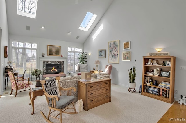 living area with carpet, visible vents, high vaulted ceiling, a premium fireplace, and a skylight