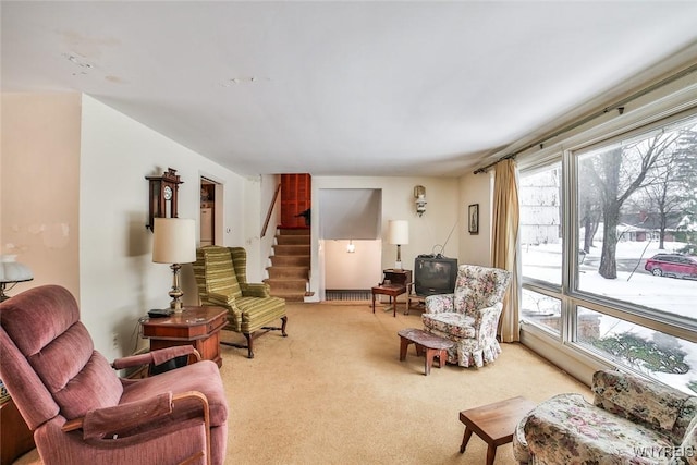 living area with stairs and light carpet