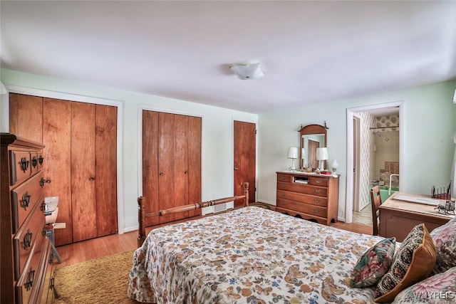 bedroom with light wood-style floors, two closets, and connected bathroom