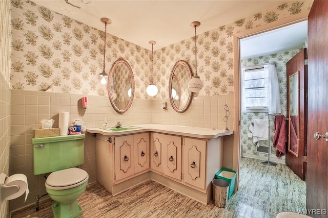 bathroom with vanity, a wainscoted wall, wallpapered walls, tile walls, and toilet