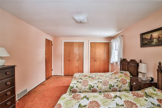 carpeted bedroom featuring visible vents, baseboards, and two closets