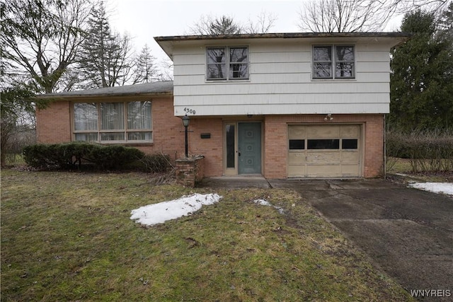 split level home featuring a front yard, a garage, brick siding, and driveway