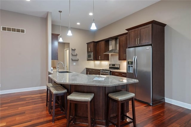 kitchen featuring visible vents, a sink, stainless steel appliances, dark brown cabinetry, and wall chimney range hood