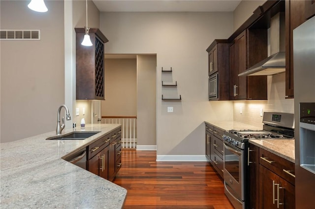 kitchen with visible vents, a sink, appliances with stainless steel finishes, wall chimney exhaust hood, and light stone countertops