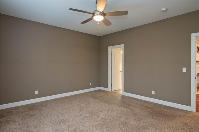 carpeted empty room with a ceiling fan and baseboards