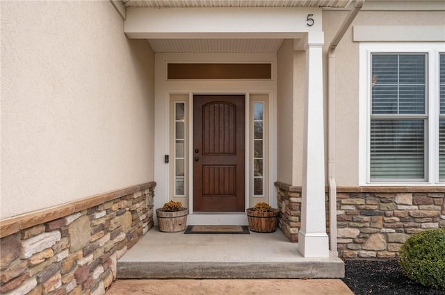 view of exterior entry with stone siding and stucco siding