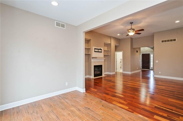 unfurnished living room with visible vents, baseboards, wood finished floors, and a fireplace