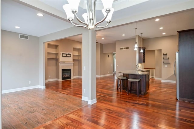 living room with visible vents, baseboards, an inviting chandelier, and dark wood-style floors