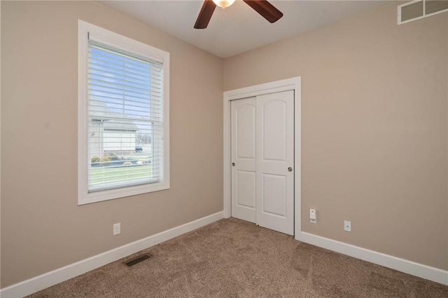 unfurnished bedroom with carpet, visible vents, a closet, and baseboards