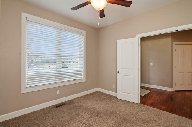 empty room featuring visible vents, a ceiling fan, baseboards, and carpet floors