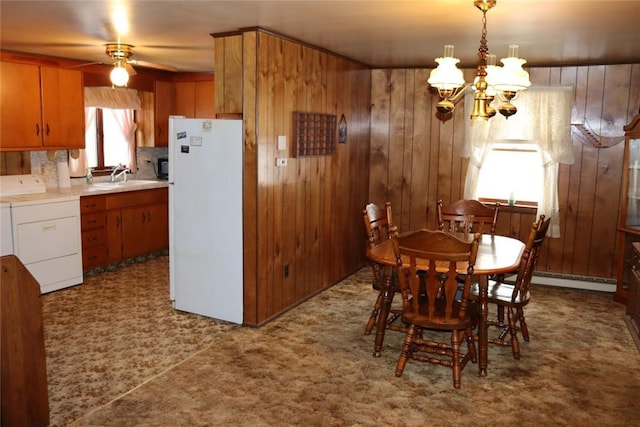 dining room featuring baseboard heating, washer / clothes dryer, wood walls, and a chandelier