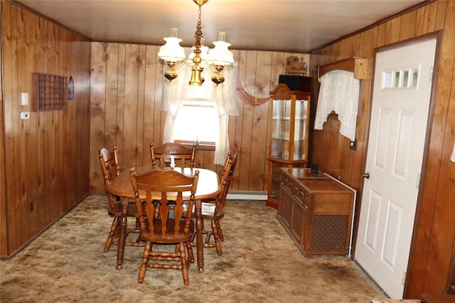 carpeted dining room with baseboard heating, an inviting chandelier, and wooden walls