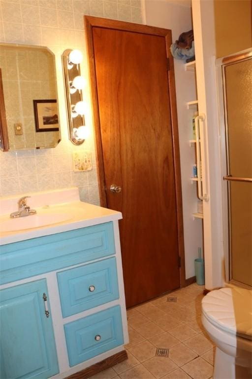 bathroom featuring tile patterned floors, toilet, tile walls, a shower stall, and vanity