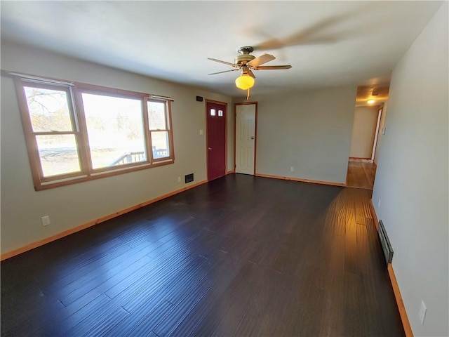 spare room with ceiling fan, baseboards, and dark wood-style flooring