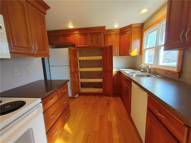 kitchen featuring brown cabinets, a sink, recessed lighting, white appliances, and light wood finished floors