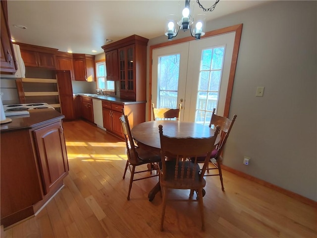 dining area featuring light wood finished floors, baseboards, recessed lighting, french doors, and a notable chandelier