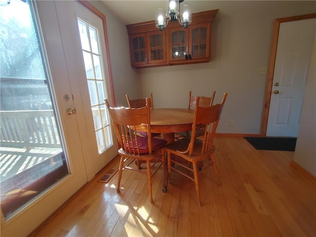 dining room featuring baseboards, light wood-style floors, and a chandelier