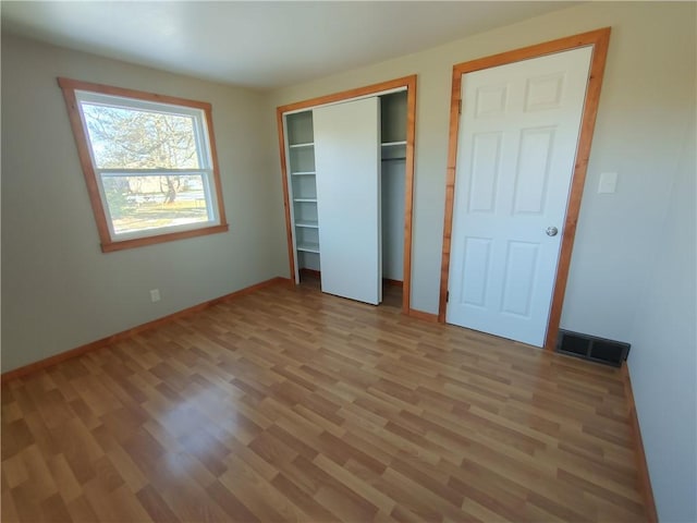 unfurnished bedroom with a closet, baseboards, visible vents, and light wood finished floors