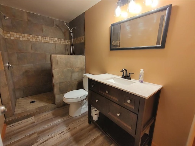 bathroom featuring vanity, toilet, wood finished floors, and walk in shower