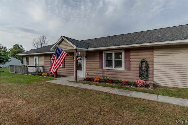 ranch-style home featuring a front yard and roof with shingles