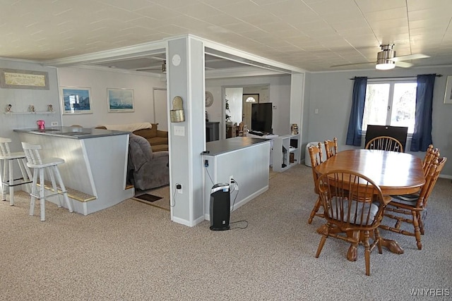 dining room featuring a bar, crown molding, and carpet flooring