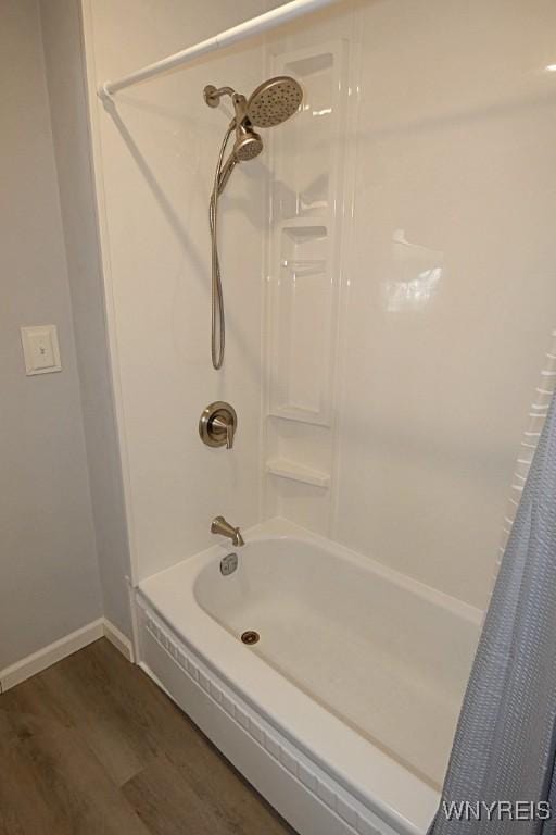 full bathroom featuring wood finished floors, shower / bath combo with shower curtain, and baseboards