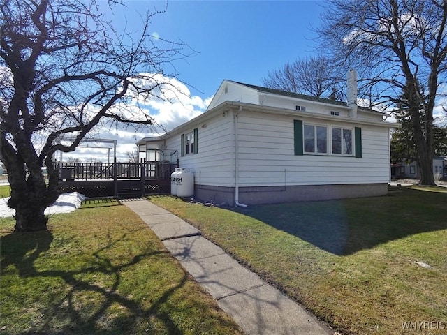 view of side of home featuring a yard and a wooden deck