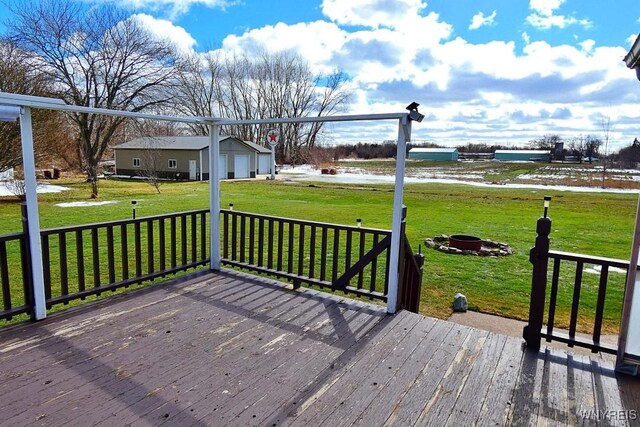 wooden deck with a yard, an outbuilding, a fire pit, and a garage