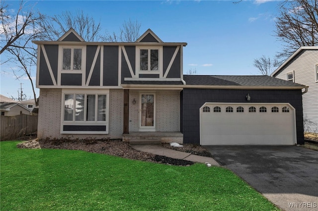 tudor home with aphalt driveway, an attached garage, brick siding, and a front yard