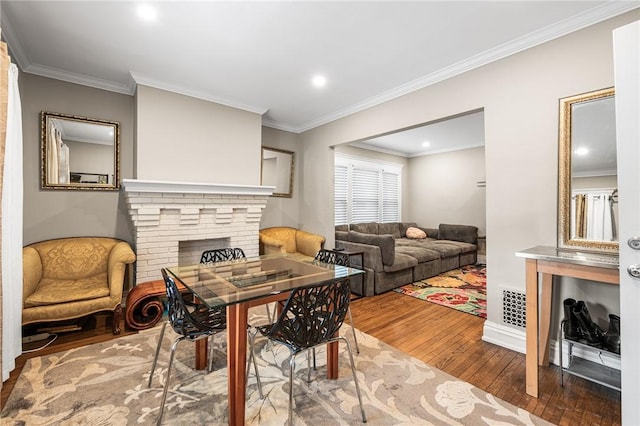 dining space with visible vents, wood-type flooring, ornamental molding, and a fireplace