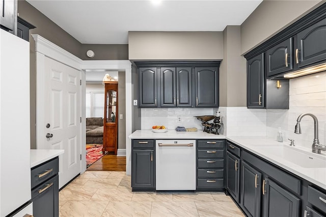 kitchen featuring white dishwasher, a sink, light countertops, marble finish floor, and tasteful backsplash