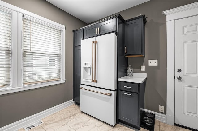 kitchen featuring visible vents, marble finish floor, white refrigerator with ice dispenser, light countertops, and baseboards