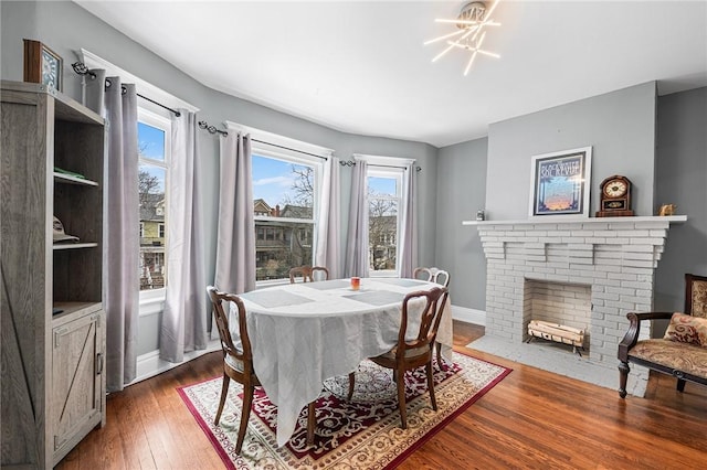 dining area with a brick fireplace, baseboards, dark wood-style flooring, and a wealth of natural light