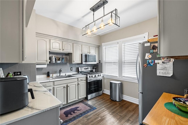 kitchen featuring tasteful backsplash, baseboards, appliances with stainless steel finishes, dark wood-style floors, and a sink