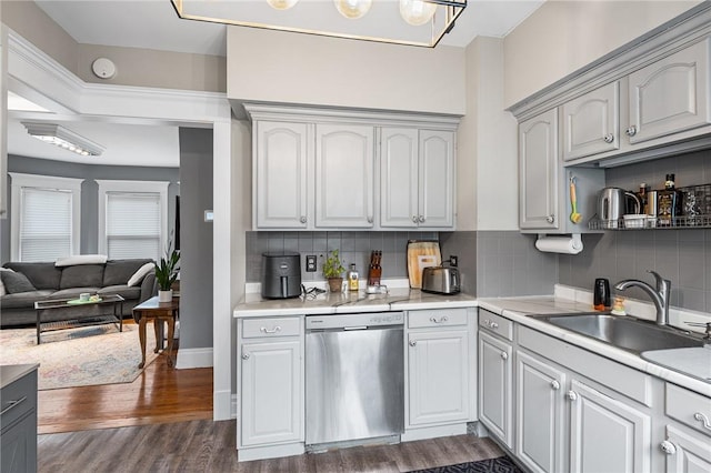 kitchen with dark wood-style floors, a sink, decorative backsplash, light countertops, and dishwasher