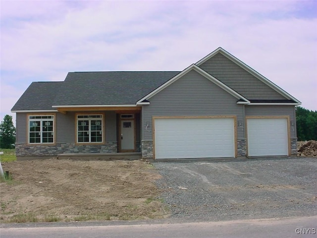 view of front of house featuring aphalt driveway, stone siding, and an attached garage