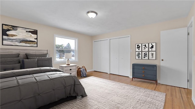 bedroom with light wood-style flooring and two closets