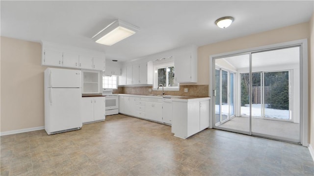 kitchen featuring a sink, white appliances, white cabinets, decorative backsplash, and baseboards