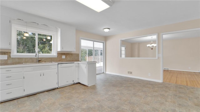 kitchen with light countertops, white dishwasher, backsplash, and a sink